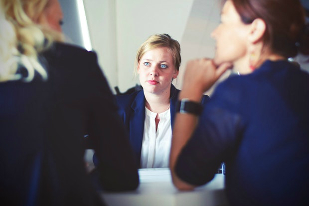 3 women sitting around a meeting table.